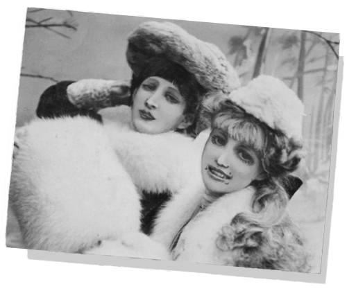 a black and white photo of marina and another woman. both are wearing fur coats and hats. marina is smiling at the camera while the other woman holds a more neutral expression.